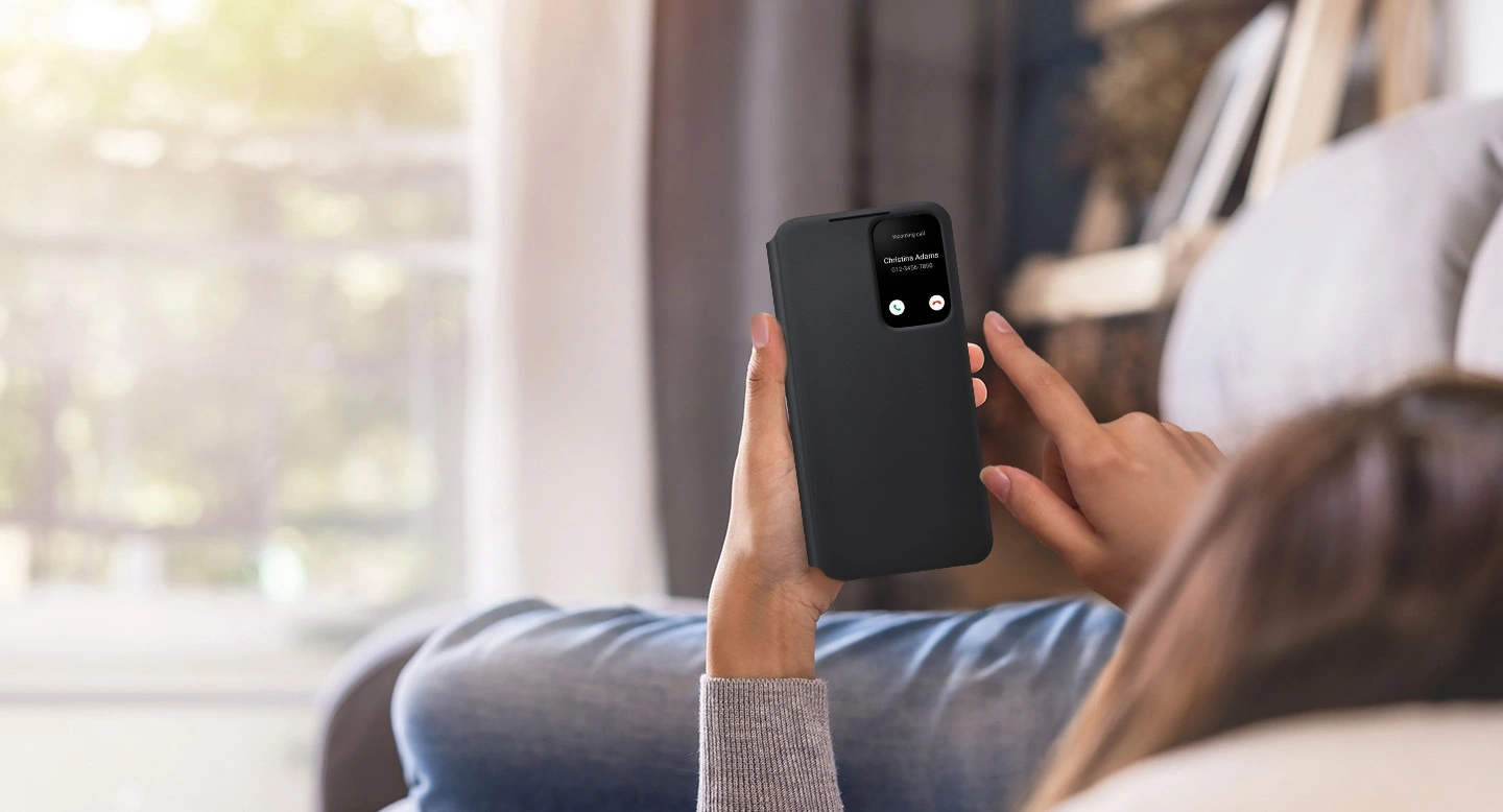 Девушка на диване пользуется своим Galaxy S22+ с чехлом Smart Clear View Cover
