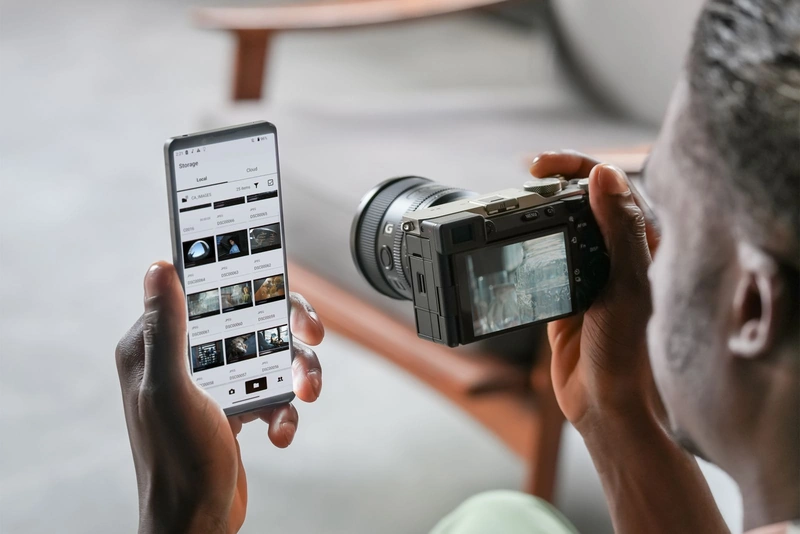 Изображение мужчины, который передаёт фотографии с камеры на смартфон