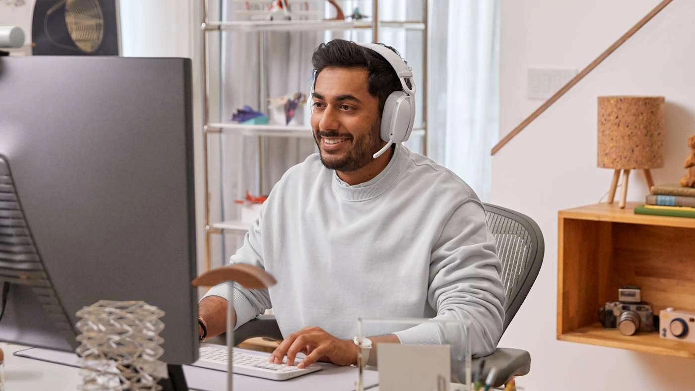 Чоловік у навушниках Logitech Zone Vibe 100 за комп’ютером