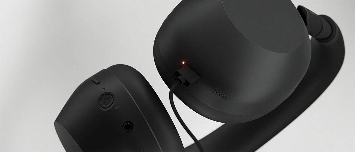 Крупный план чашек чёрных наушников Sony WH-1000XM6 с кнопкой питания и подключённым кабелем