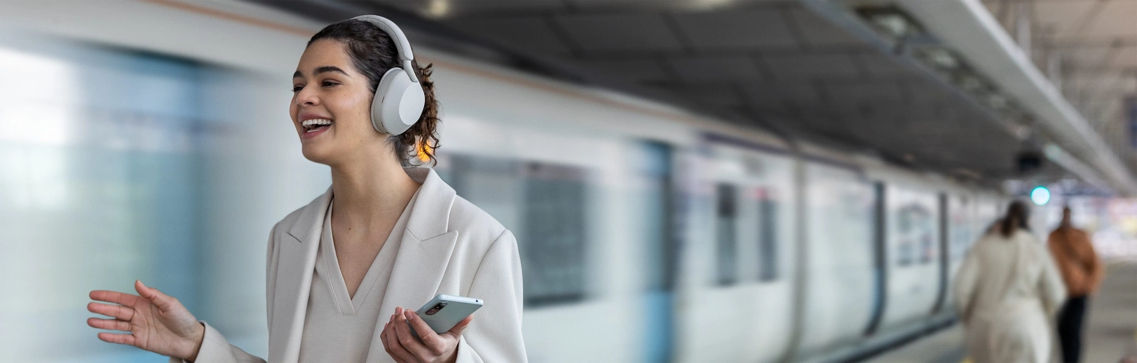 Девушка разговаривает по телефону в наушниках Sony WH-1000XM5 в метро