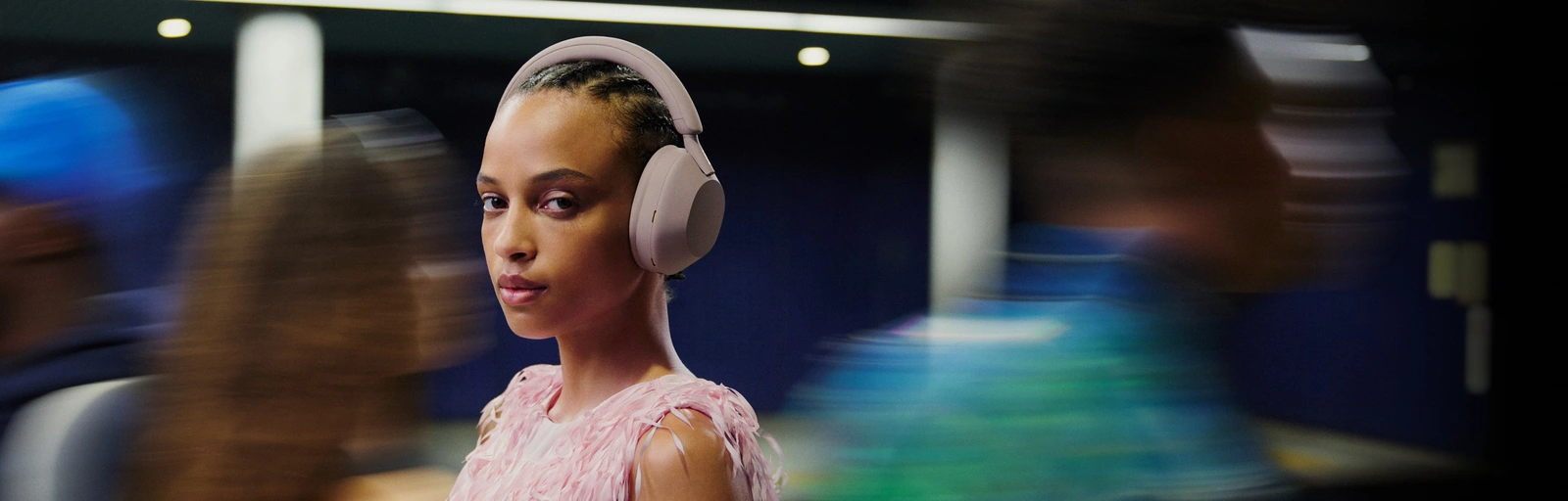 Девушка в наушниках Sony WH-1000XM5 с включённым шумоподавлением на улице