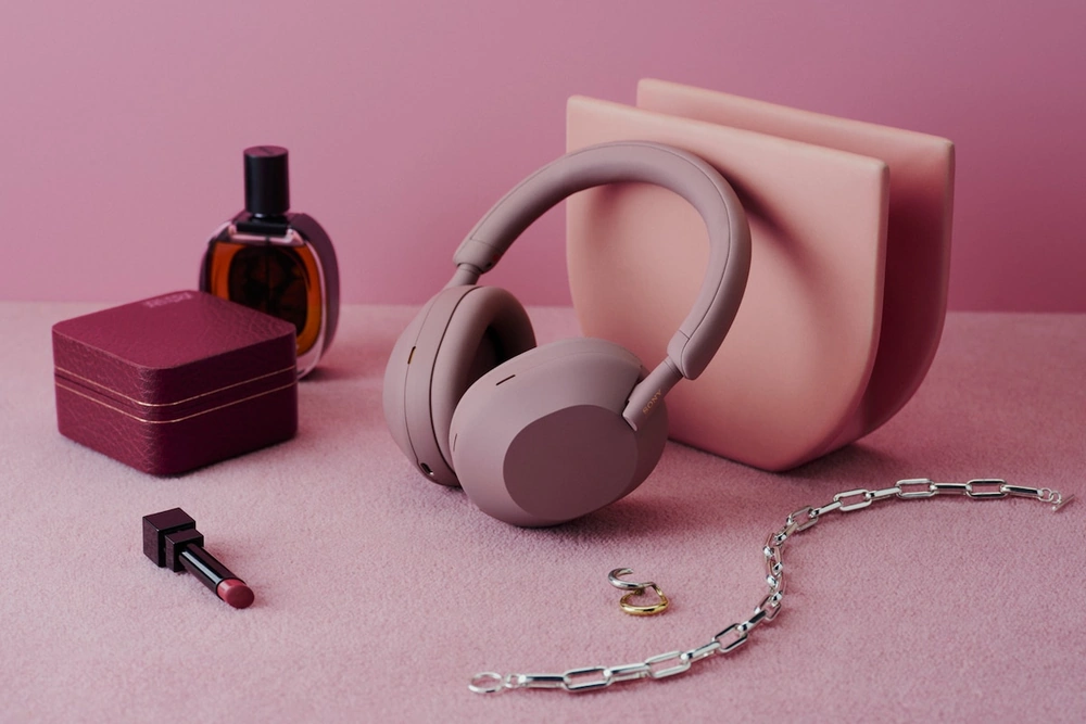 Наушники Sony WH-1000XM5 дымчато-розового цвета рядом с косметикой