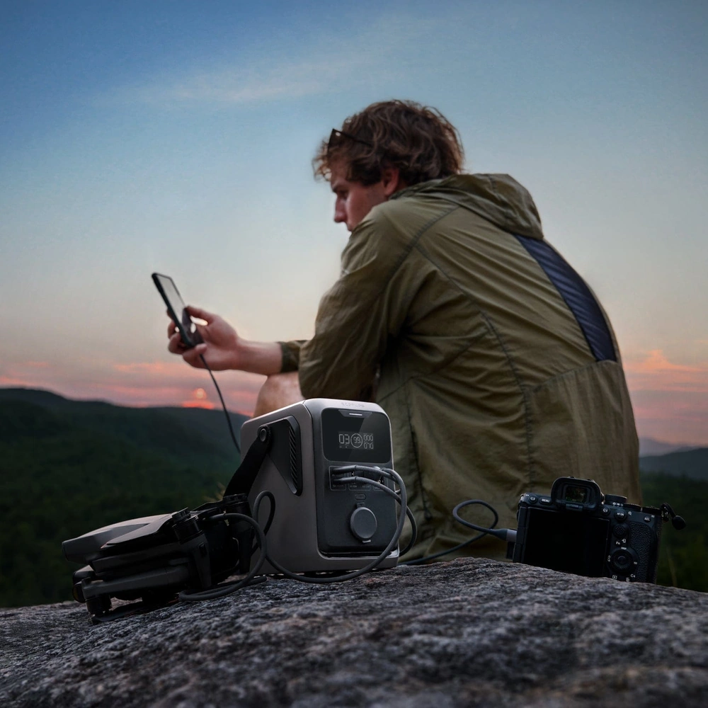 Фотограф заряжает камеру от станции EcoFlow TRAIL 300 DC в горах