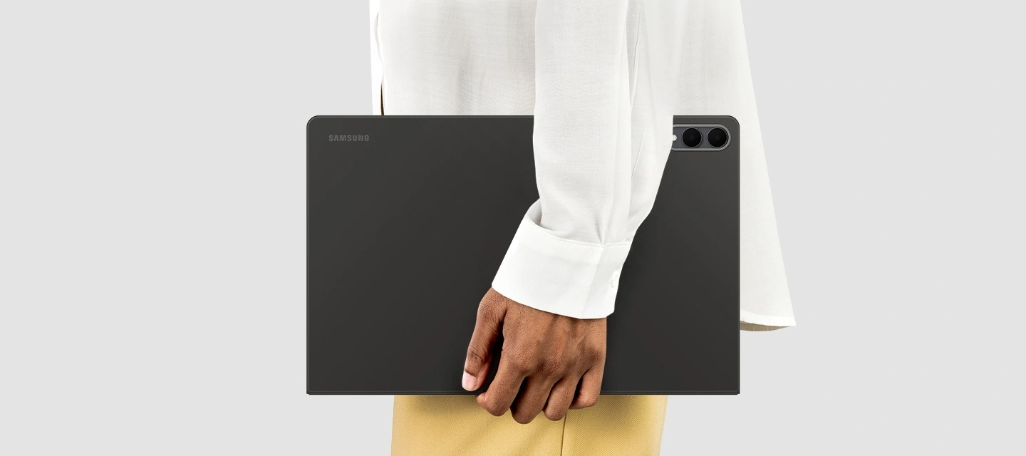 Человек держит Galaxy Tab S11 Ultra в чехле-книжке, ракурс сбоку подчёркивает его тонкий и лёгкий дизайн, удобный для использования в дороге.