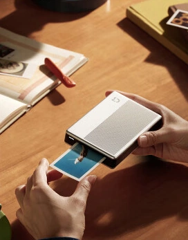 Руки держат фотопринтер MiJia Pocket 1S и напечатанное фото