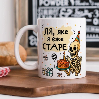 Біла керамічна чашка з дизайном "Ля, яке я вже старе"